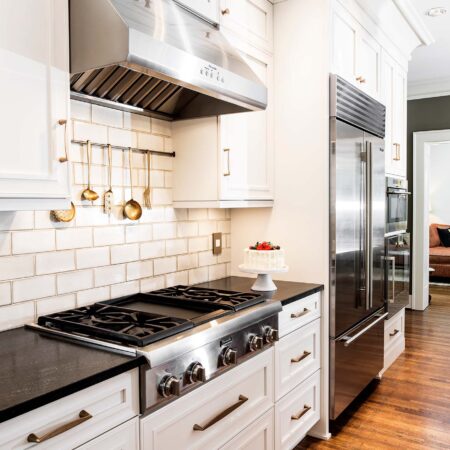 Tulsa kitchen design and remodel featuring a Thermador professional gas rangetop, a vent hood, a subway tile backsplash, a stainless steel Sub-Zero refrigerator and freezer, and Wolf and Gaggenau ovens.