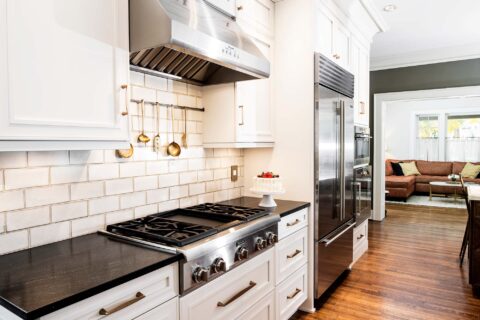 Tulsa kitchen design and remodel featuring a Thermador professional gas rangetop, a vent hood, a subway tile backsplash, a stainless steel Sub-Zero refrigerator and freezer, and Wolf and Gaggenau ovens.