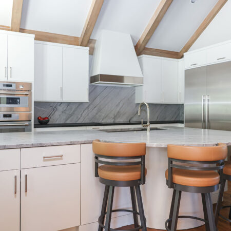 Vaulted ceiling Tulsa kitchen remodel featuring a large island with seating, maple cabinets, and a custom vent hood.