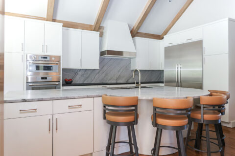 Vaulted ceiling Tulsa kitchen remodel featuring a large island with seating, maple cabinets, and a custom vent hood.
