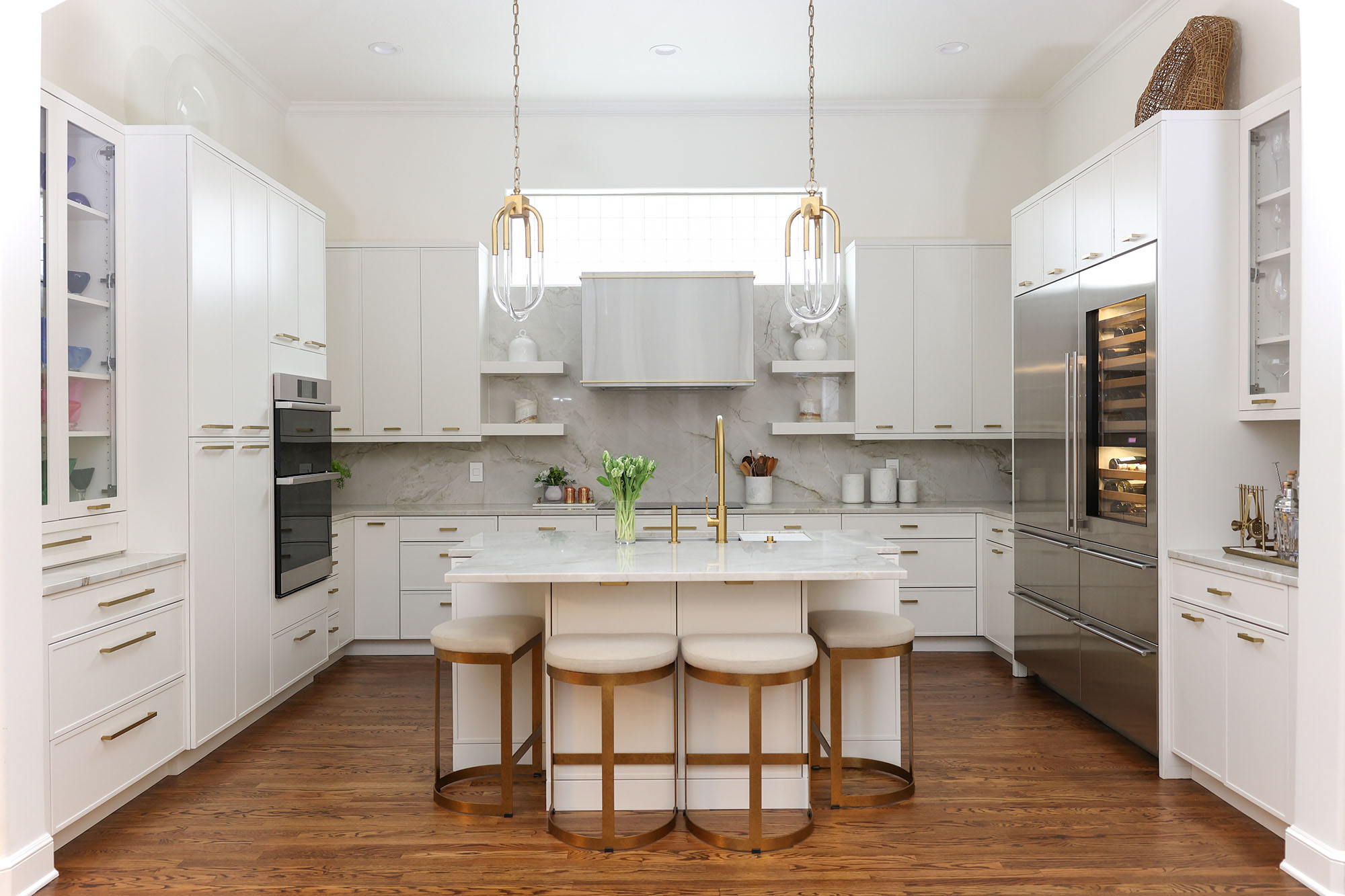 Open white kitchen featuring island with seating, decorative pendant lighting, and premium Dacor Sub-Zero Wolf appliances in Tulsa kitchen design and remodel.